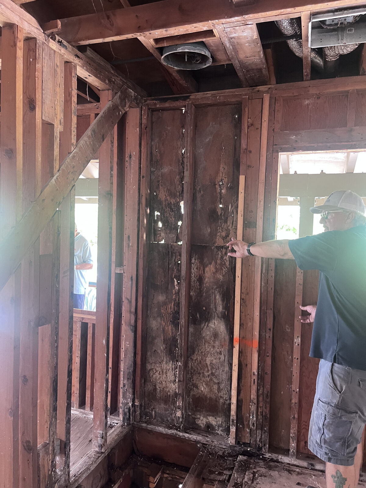 Renovation crew member walking past the chapter house during the remediation phase, exposed framing visible